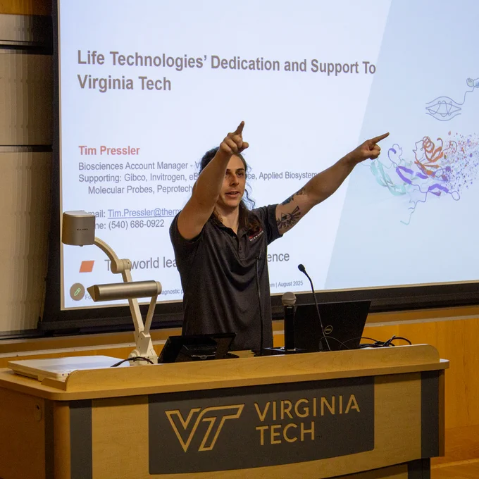 A guy points to the audience while presenting his research. 