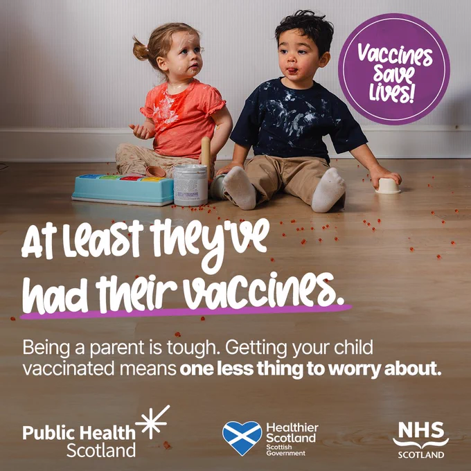Two toddlers sit on a wooden floor with scattered toys, highlighting the importance of childhood vaccinations.