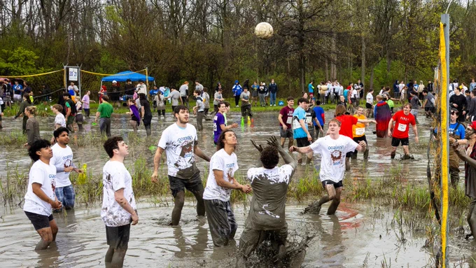 A team of people playing volleyball in the mud.