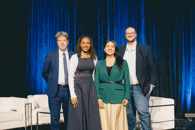 Four people stand together on a stage.
