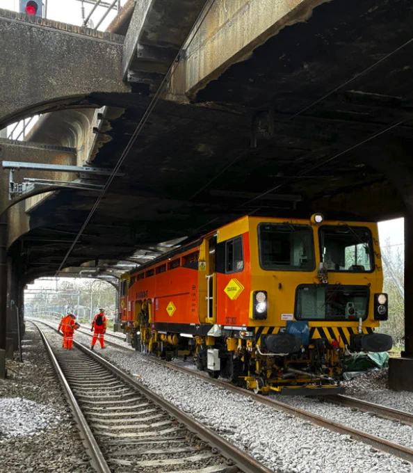 Tamping newly replaced track just outside Ilford. A tamper is visible, along with new rails and fresh ballast.