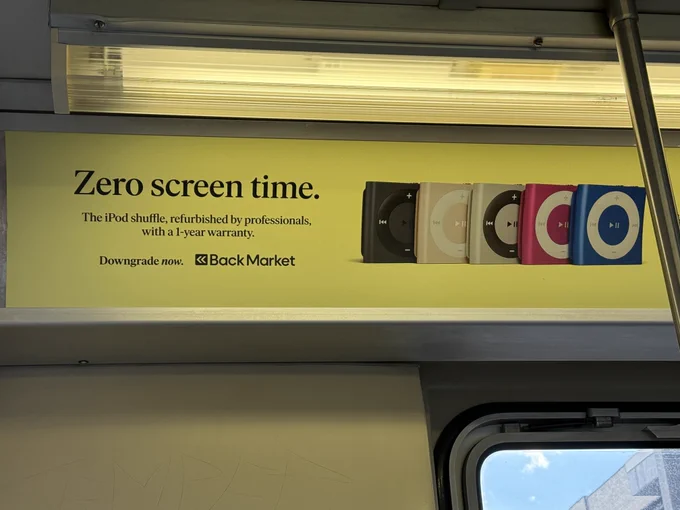 Professionally produced and placed advert on a CTA train for a business that sells "professionally refurbished" iPod shuffles. "Zero screentime, downgrade now" boasts the text.