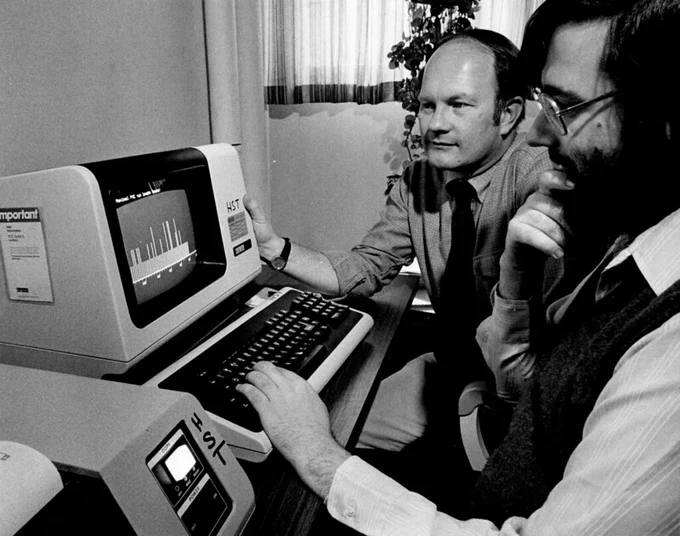Black and white photo of Roger Mark (left) and George Moody (right) looking at a monitor.