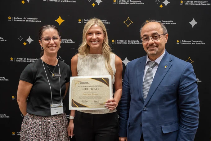 Kristina Childs, Mackenzie Masters and Naim Kapucu standing in front of a black CCIE-branded backdrop. Masters is holding a Research Impact Showcase presenter certificate.