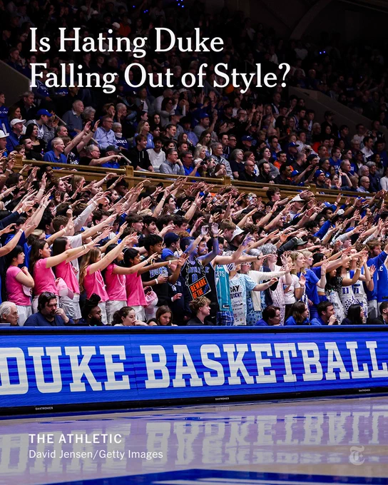 Duke Blue Devils fans cheer with their hands up in the stands during a basketball game. Text reads: Is Hating Duke Falling Out of Style?