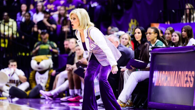 Coach Kim Mulkey energetically coaching on the sidelines of a basketball game. 