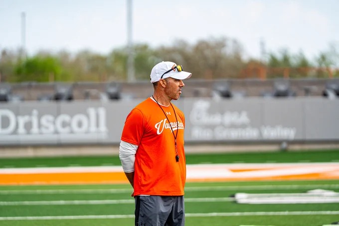 Coach standing on the field watching practice.