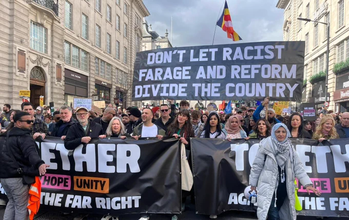 Image of Jeremy Corbyn, Zarah Sultana, Zack Polanski and other left MPs and leaders at the front of the Together march

In the background  is a banner: DON'T LET RACIST FARAGE AND REFORM DIVIDE THE COUNTRY