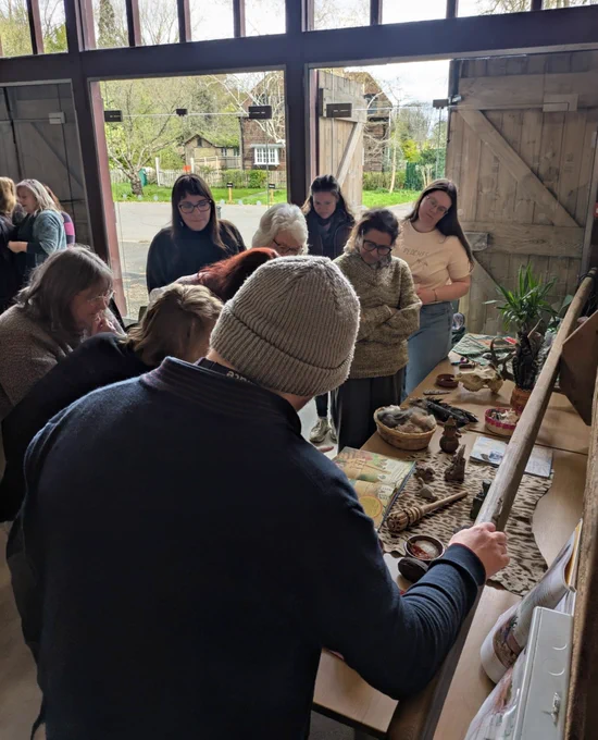 Group of adults stood looking at a long table packed with different artefacts.