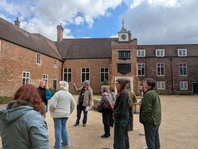 Group of adults stood in courtyard with brick build and gravel floor