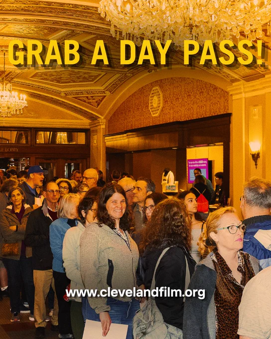A large crowd lines up inside an ornate theater lobby with chandeliers and gold decor. Bold yellow text reads “GRAB A DAY PASS!” and a website URL appears at the bottom.