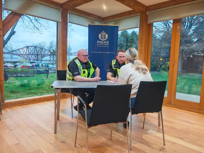 Two police officers speak to a member of the public in a police drop in session.