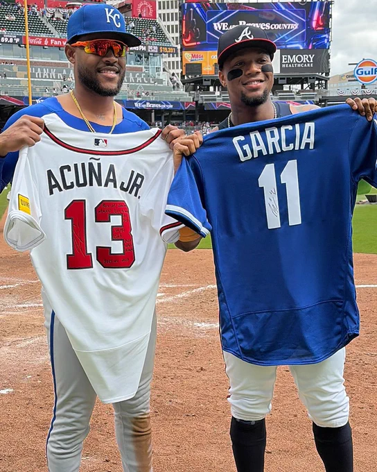 Ronald Acuña Jr. and Maikel Garcia pose for a photo after signing and swapping jerseys following this weekend's matchup between the Braves and the Royals. Garcia holds up Acuña Jr.'s white Atlanta Braves jersey, and Acuña Jr. holds up Garcia's blue Kansas City Royals jersey.