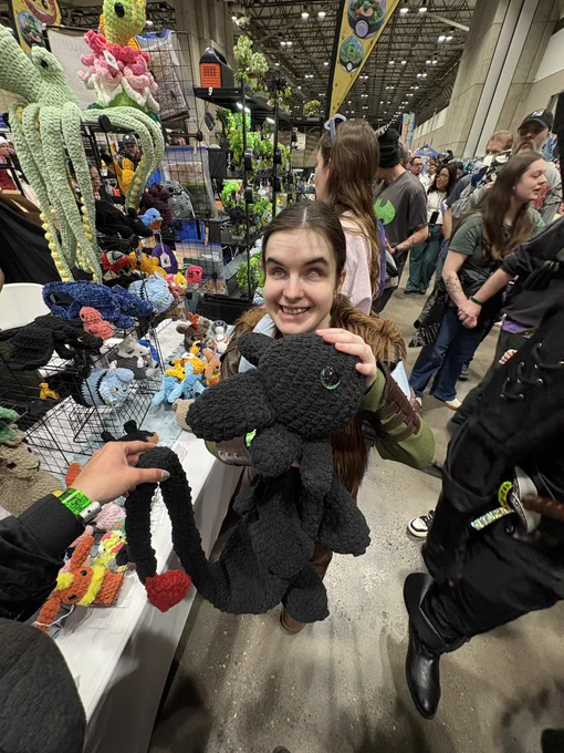 Me holding a crochet Toothless. I'm holding my left hand with my palm facing out and Toothless's head is touching my palm, known as the Hiccup move!