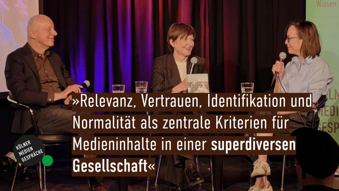 Drei Personen, zwei Frauen und ein Mann, sitzen auf einem Podium und diskutieren.