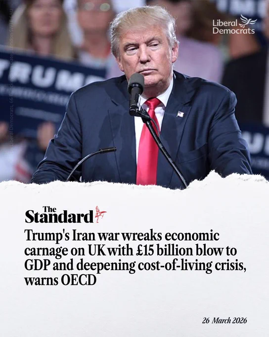 A graphic showing Donald Trump speaking at a podium with a microphone, wearing a navy suit and red tie, with a blurred crowd behind him.

Overlaid text from The Standard reads: “Trump’s Iran war wreaks economic carnage on UK with £15 billion blow to GDP and deepening cost-of-living crisis, warns OECD.”