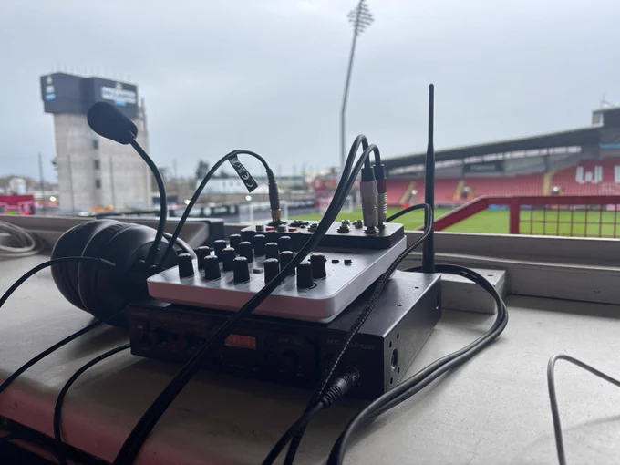 Commentary equipment sat on a desk top with an empty stand in the background
