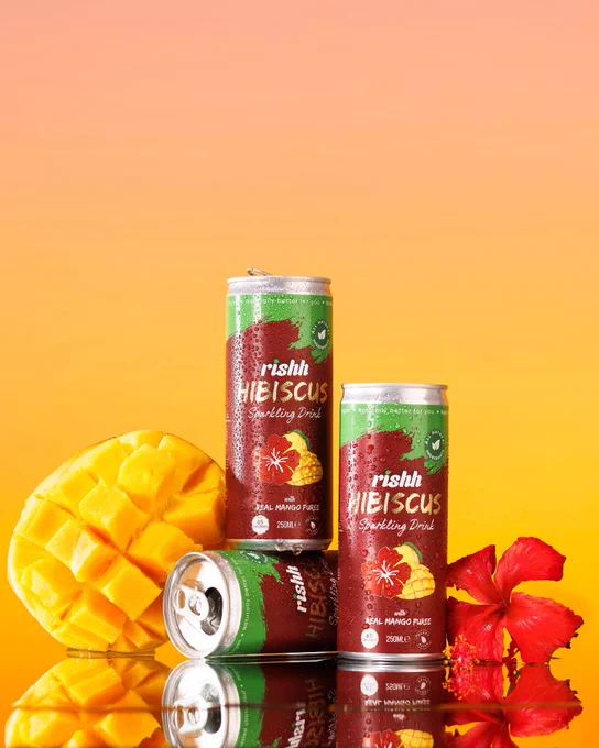 Product image of the Mango flavoured Rishh Hibiscus drink. The image is styled using the drink ingredients; hibiscus and mango. The image is by Aisha Ife