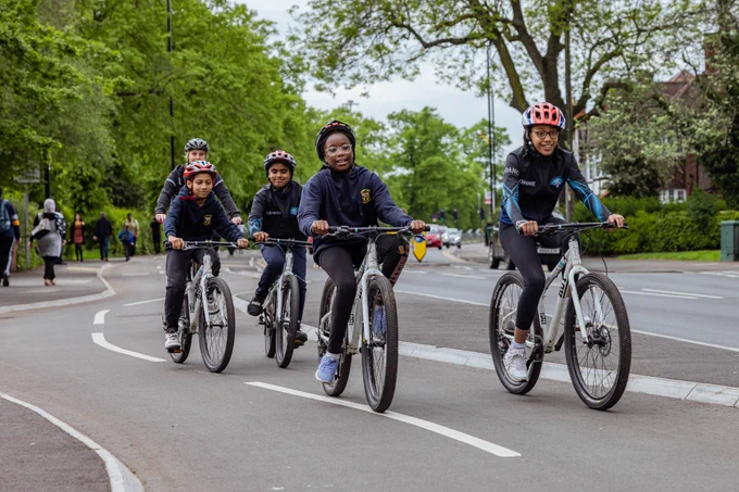 A group of children cycle along a segregated cycle lane.