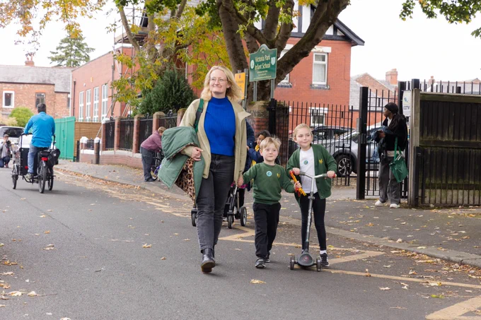 A mum and two children outside a school.