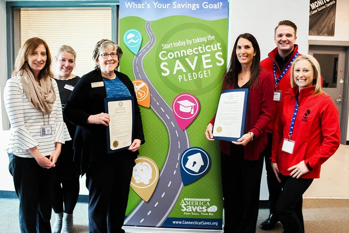 six people holding two certificates and smiling in front of a CT Saves banner