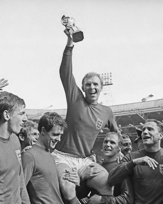 Black and white image of Bobby Moore player lifted by England teammates after winning the world cup. 
