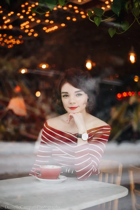 A person sits at a table with a mug in front of them.
