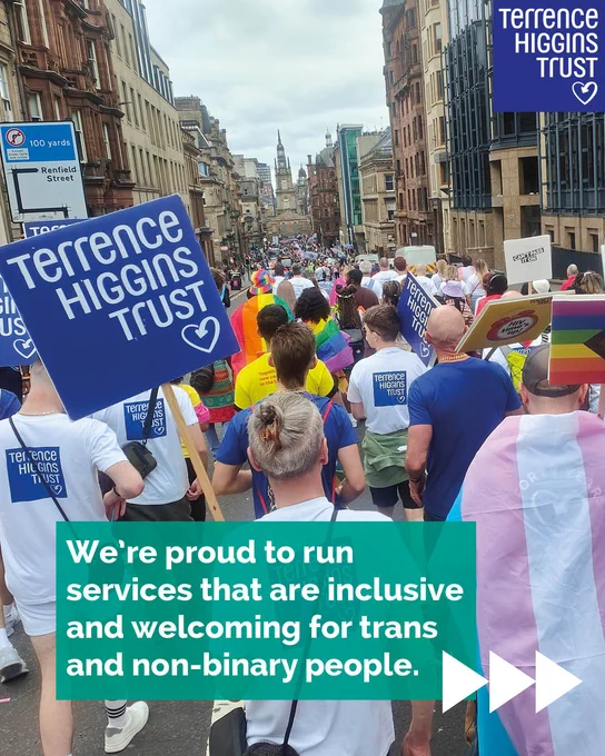 Parade crowd with Pride flags and Terrence Higgins Trust signs.