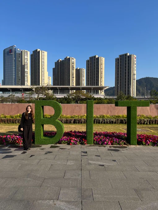 Zuzanna next to the BIT logo with a panoramic view of the city's buildings in the distance