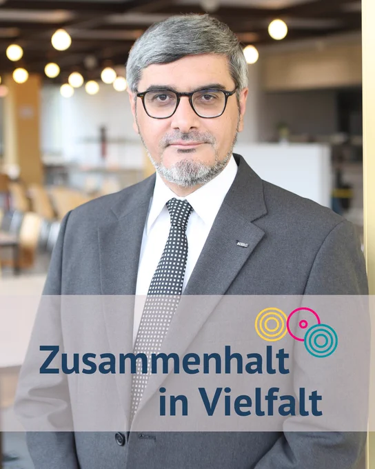 Porträt von Ali Mete, davor das Banner "Zusammenhalt in Vielfalt" mit den drei bunten Kreisen