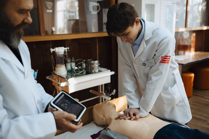 A medical student practices cardiopulmonary resuscitation on a high-tech simulation mannequin at Kremenchuk Medical College, while an instructor monitors the results on a digital device.