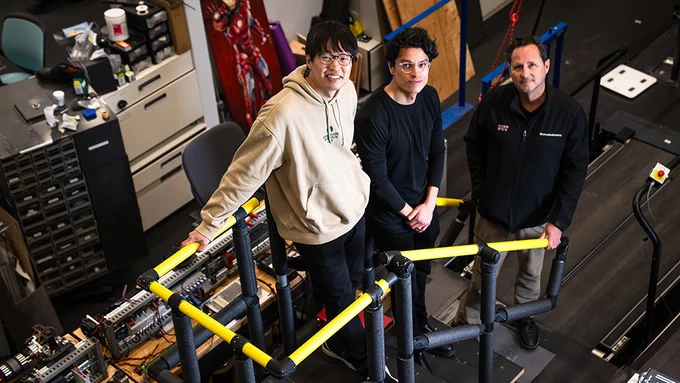 Three researchers stand on a makeshft staircase in a bionics lab setting. 