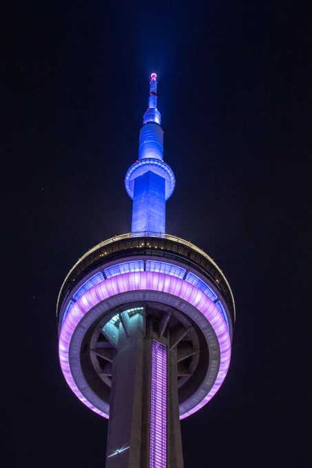 Closeup of the CN Tower at night lit light blue, pink and white / Gros plan de la Tour CN illuminée en bleu clair, rose et blanc la nuit 