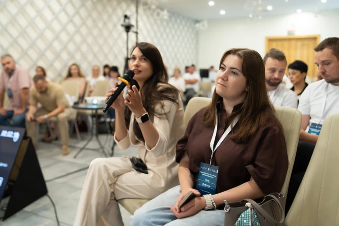 Maryna Bobranitska, Head of the Department for the Systemic Development of Administrative Services at the Ministry of Digital Transformation of Ukraine, asks a question during a panel discussion at the First Mykolaiv Digital Forum, while other participants listen attentively in a packed conference room.
