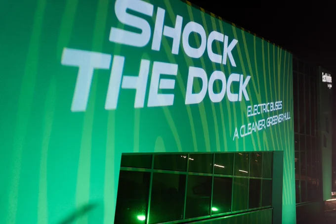 The words "Shock the Dock - electric buses, a cleaner, greener Hull" displayed on the side of The Deep in Hull.