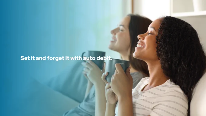 

Two people relaxing on a couch, smiling and holding mugs. Text on the image reads, "Set it and forget it with auto debit." The background features a gradient blue overlay.