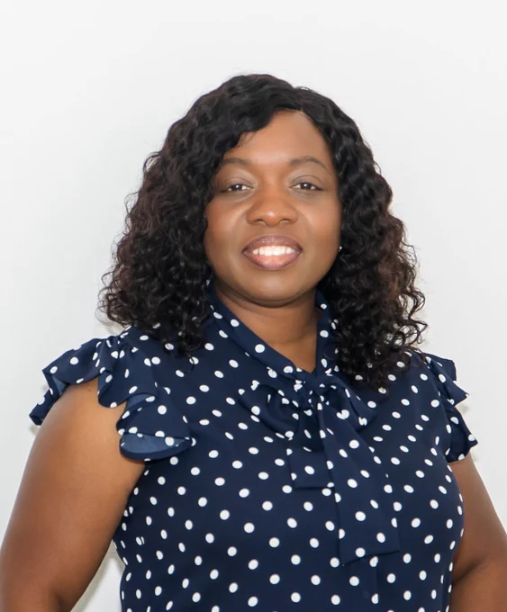Head shot of Adaobi Moemenam, smiling, wearing a blue polka dot blouse. 