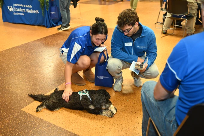 Two students petting a therapy dog.