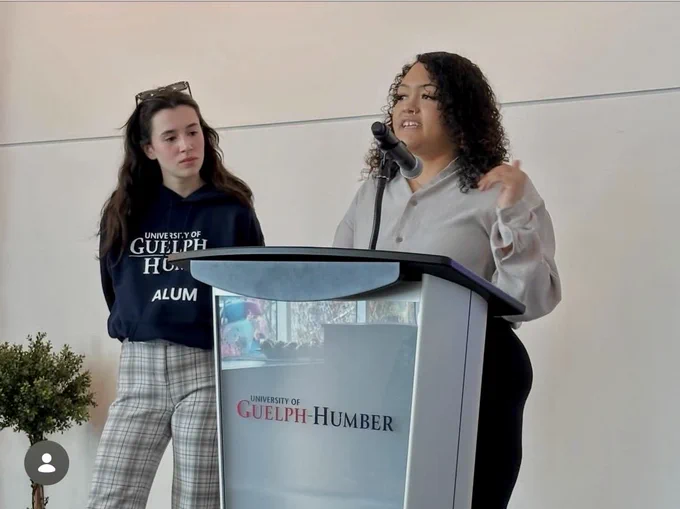 Two students standing at a podium, presenting their research.