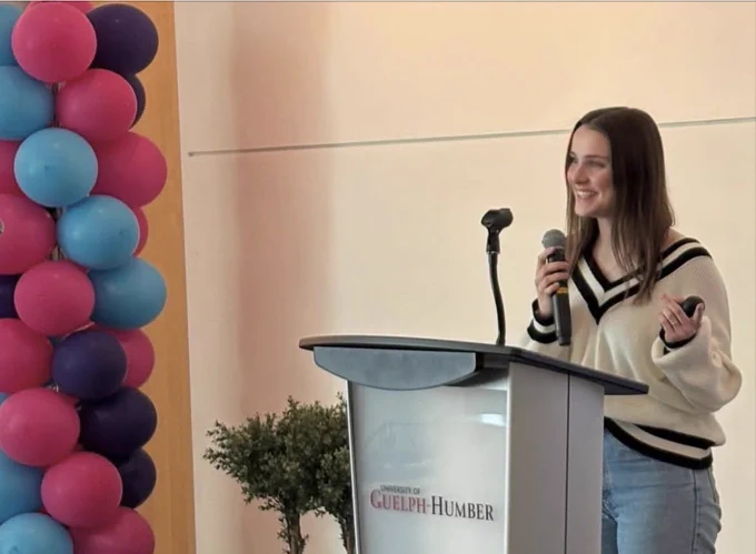A student standing in front of a podium, presenting her research project.