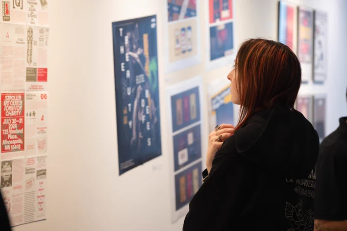 Photo of an individual looking at art pieces hung on a wall.