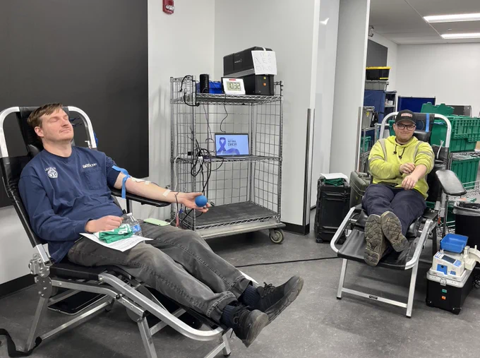 Two AES Ohio employees donate blood at the same time, seated in separate chairs at a blood drive.