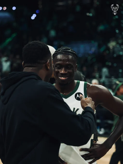 Brothers Thanasis and Alex Antetokounmpo celebrating after a Bucks win at Fiserv Forum.