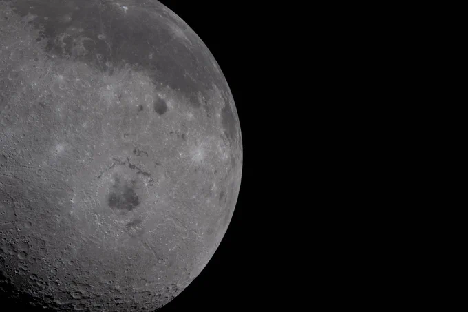 Just over half of the Moon fills the left half of the image. The near side, characterized by the dark patches of ancient lava, is visible on the top third of the lunar disk. Orientale basin, a round crater in the center with a black patch of ancient lava in the center, is wrapped in rings of mountains. The round black spot northeast of Orientale is Grimaldi crater, and Aristarchus crater is the bright white dot in the midst of a dark grey lava flow at the top of the image. Credit: NASA