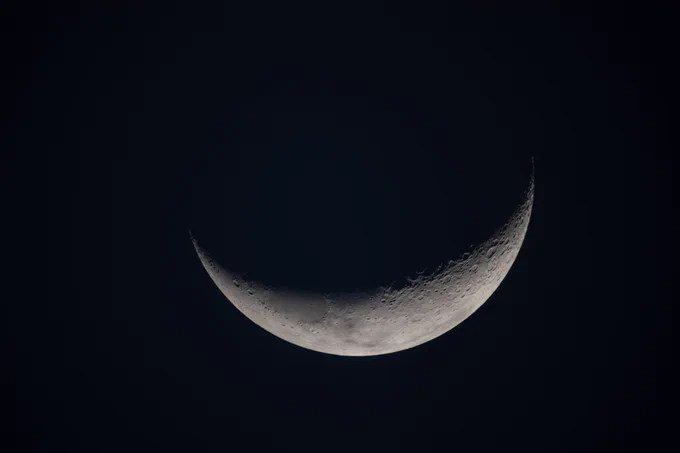 On flight day seven, following their lunar flyby, the Artemis II crew captured this view of a delicate crescent Moon on their journey back to Earth. Along the terminator—the boundary between lunar day and night—low-angle sunlight casts long shadows that accentuate craters, ridges, and subtle variations in terrain. The softly illuminated surface highlights the Moon’s rugged landscape, while much of it remains in shadow. Credit: NASA