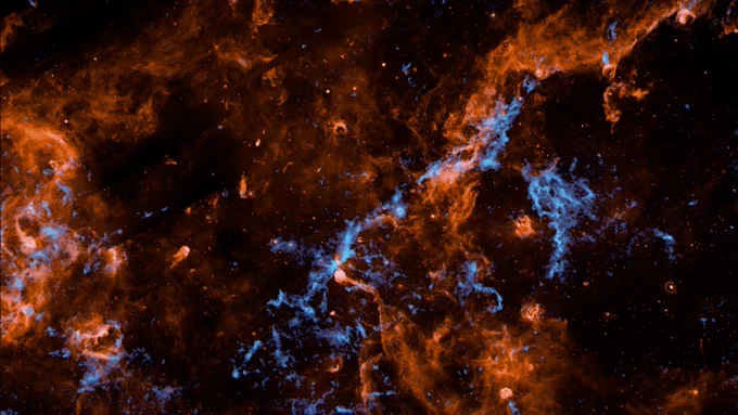 This observation made by NASA’s SPHEREx shows Cygnus X, one of the most active and turbulent regions of star birth in our Milky Way galaxy. The “interstellar glaciers” are visible in bright blue, and polycyclic aromatic hydrocarbons in orange. Image credit: NASA/JPL-Caltech/IPAC/Hora et al.