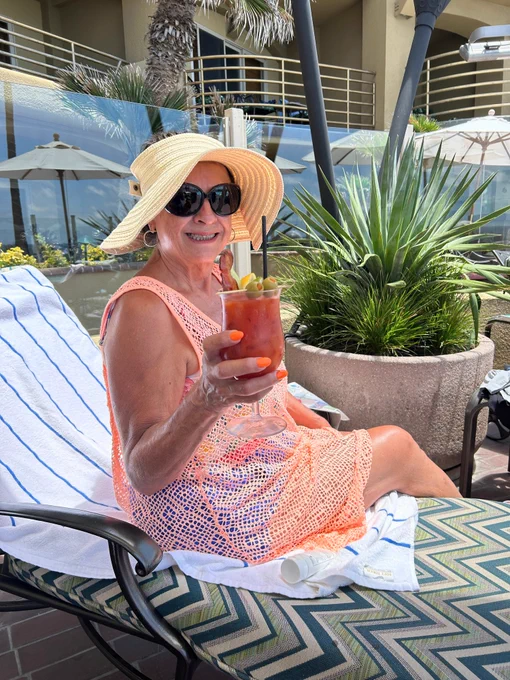 Woman sitting on beach chair with drink in hand