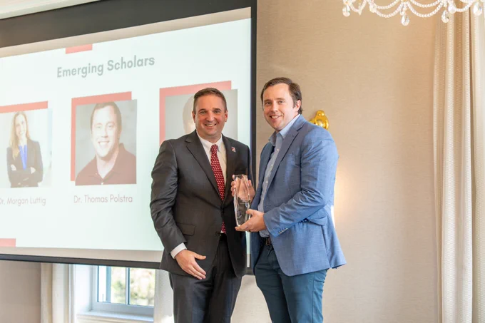 Dr. Thomas Polstra poses with his Emerging Scholar Award and the award presenter.
