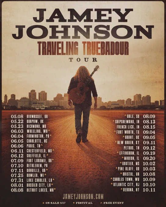 This is a tour poster for Jamey Johnson's "Traveling Truebadour Tour." It features an individual with long hair walking down a road while holding a guitar, with a skyline in the background. The tour dates and locations are listed on both sides: Hiawassee, GA; Hiwapp, OK; Richmond, IN; Washington, MO; Flemington, PA; Charlotte, NC; Wilmington, NC; Seaford, DE; Fort Lauderdale, FL; Birmingham, AL; Dothan, AL; Bossier City, LA; Forest Hill, TX; Deseret, LA; Vail, CO; Meeker, CO; Shipshewana, IN; French Lick, IN; Fort Worth, TX; Trussville, AL; Chattanooga, TN; Hinckley, MN; Dubuque, IA; Evansville, IN; Pine Bluff, AR; Louisville, KY; Arkansas City, KS; Charles Town, WV; Atlantic City, NJ; Verona, NY. The poster mentions that tickets go on sale on March 17, it is part of a festival, and it is a free event.