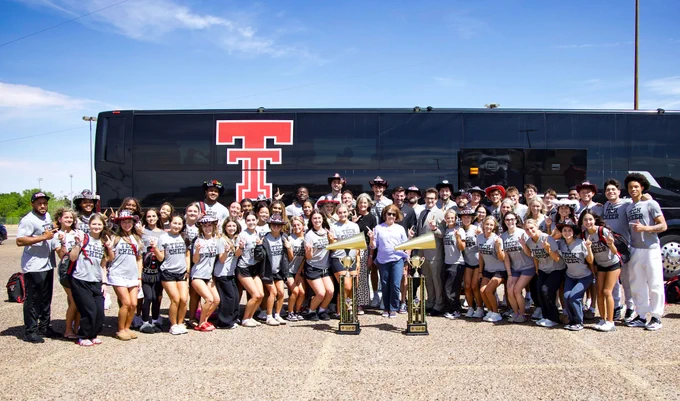 Texas Tech Cheerleading posing with Texas Tech President Lawrence Schovanec, Head Women's Basketball Coach Krista Gerlich and the two national championship trophies won over the weekend.